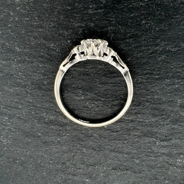 Pre-Owned: Precious white metal round brilliant cut diamond solitaire ring with diamond set shoulders.