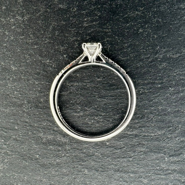 Pre-Owned: Platinum round brilliant cut diamond solitaire ring with diamond set shoulders.