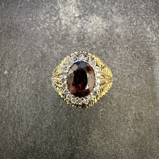 Pre-Owned: Precious yellow metal & oval cut garnet dress ring with diamond surround.