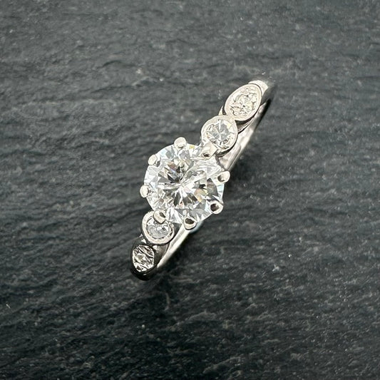 Pre-Owned: Precious white metal  round brilliant cut diamond solitaire ring with diamond set shoulders.